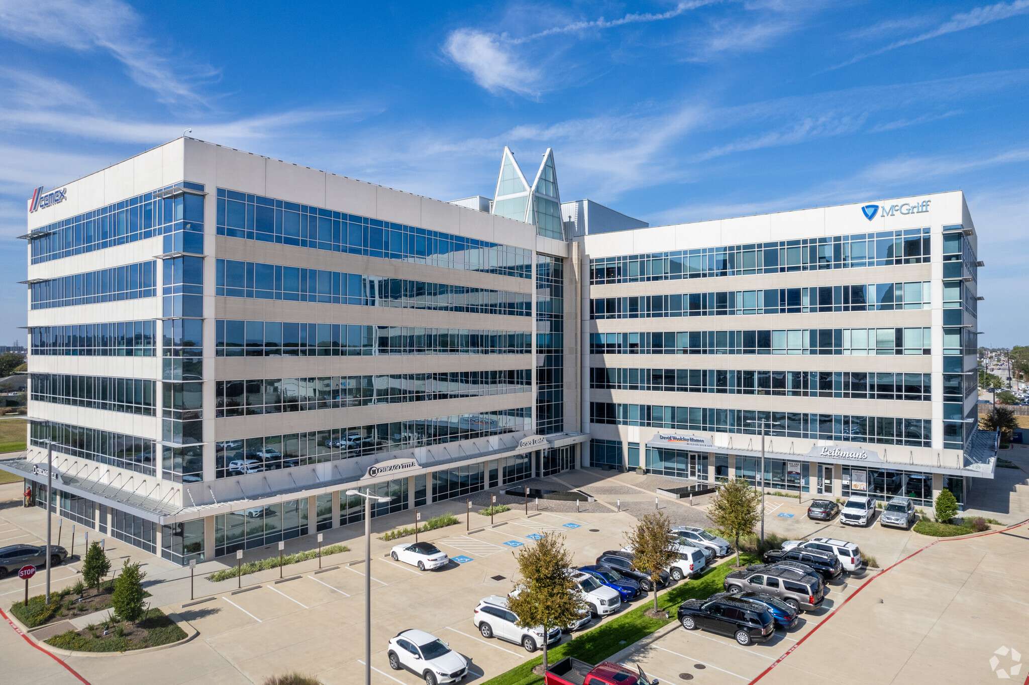 Aerial view of the glass facade and crown of 10100 Katy Freeway against a blue sky