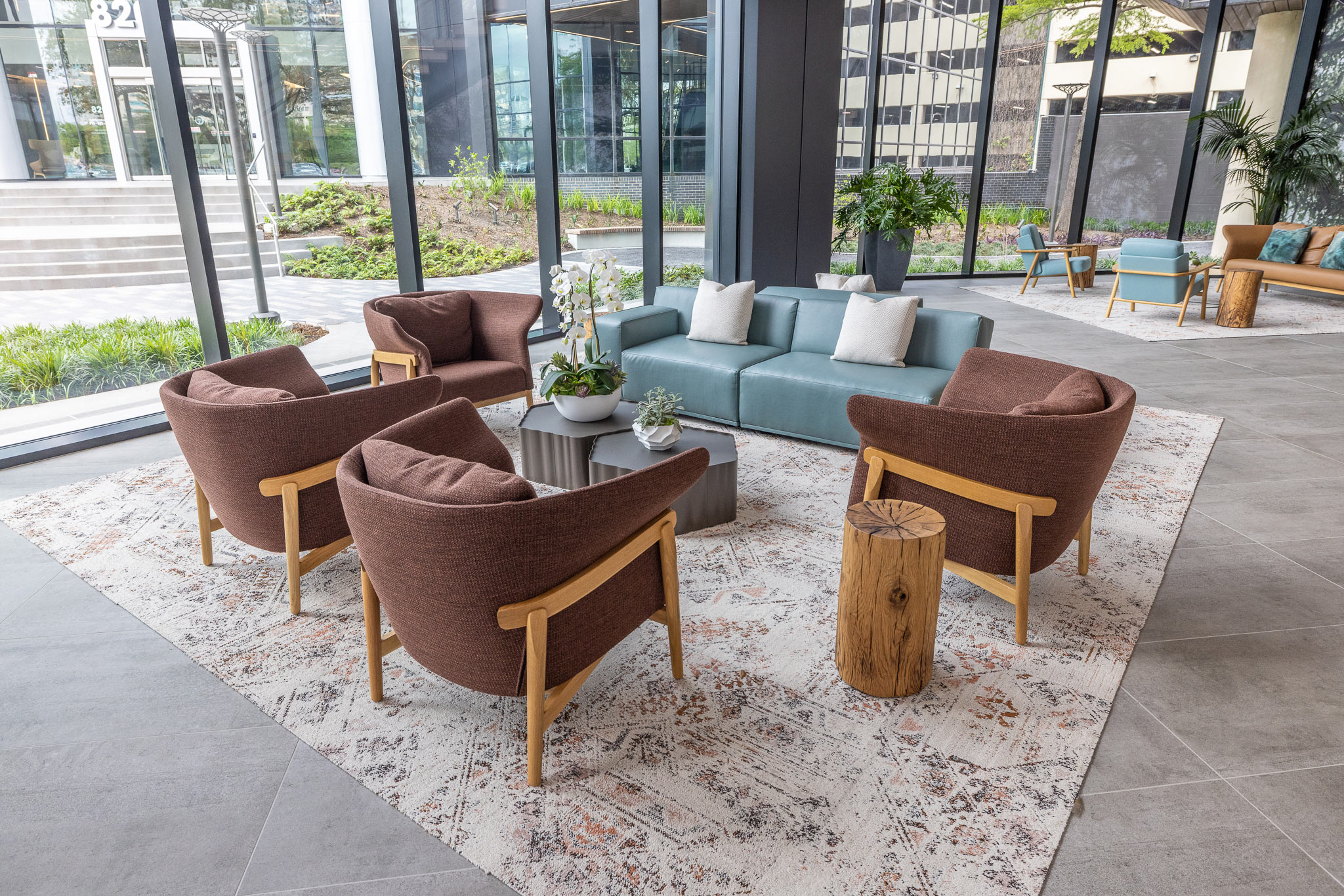 Lobby seating at 800 Gessner Road with rust armchairs and a sofa on a rug beside a glass curtain wall