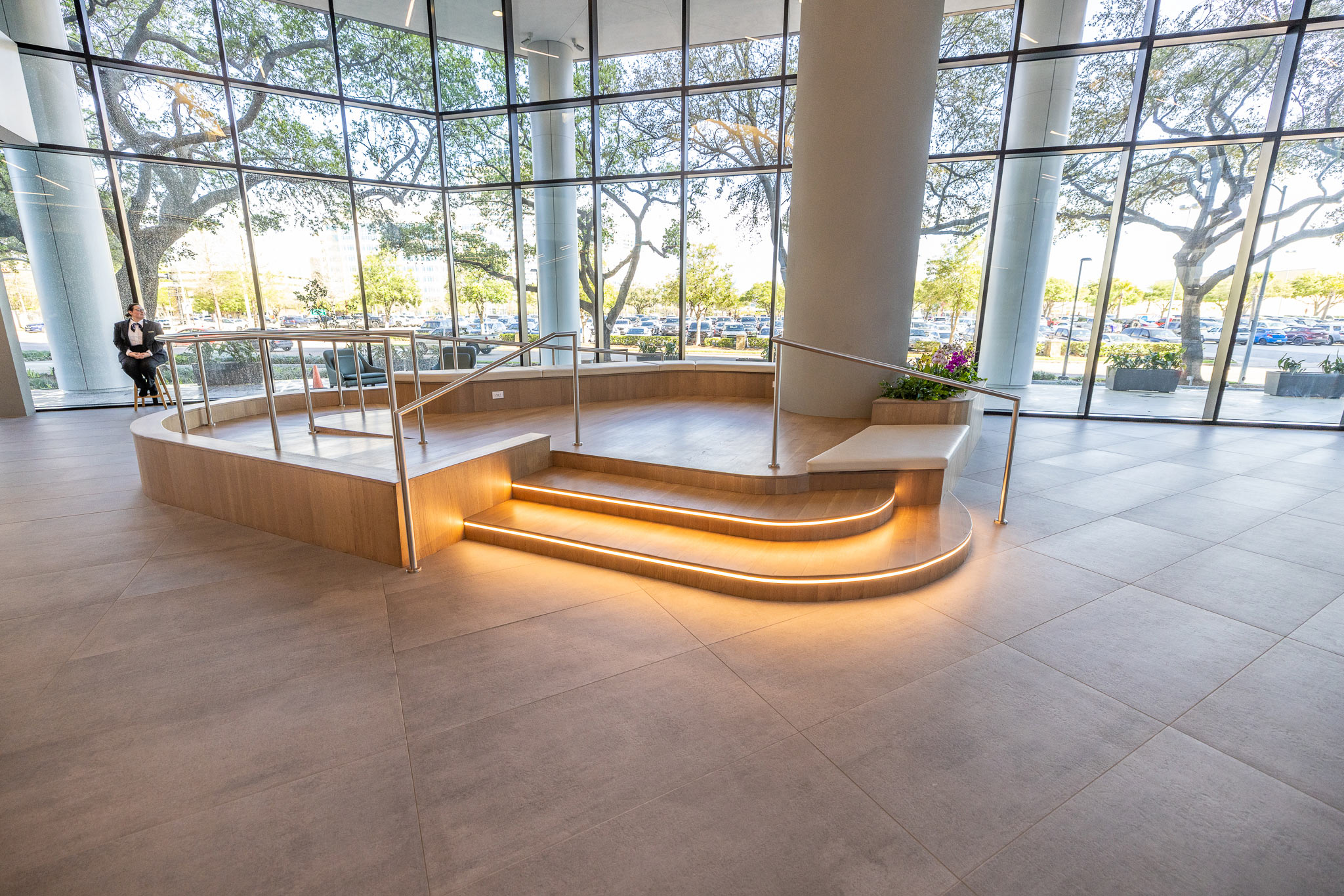 Lobby at 800 Gessner Road with a curved illuminated bench and full-height glass looking out to trees