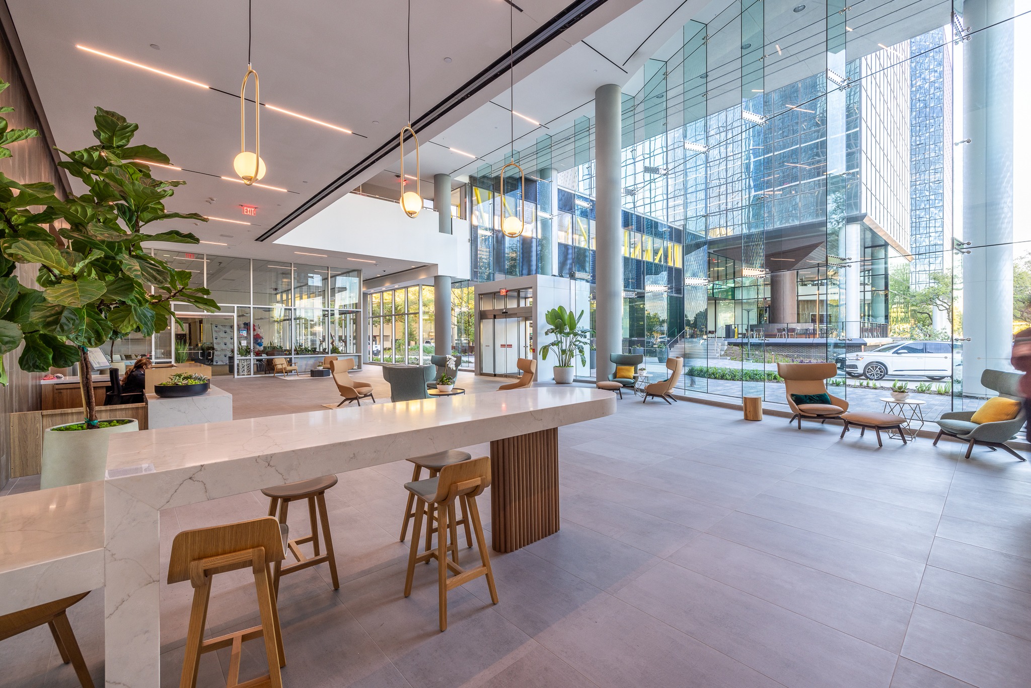 Cafe counter with wood stools in the lobby of 820 Gessner Road, beside a glass curtain wall