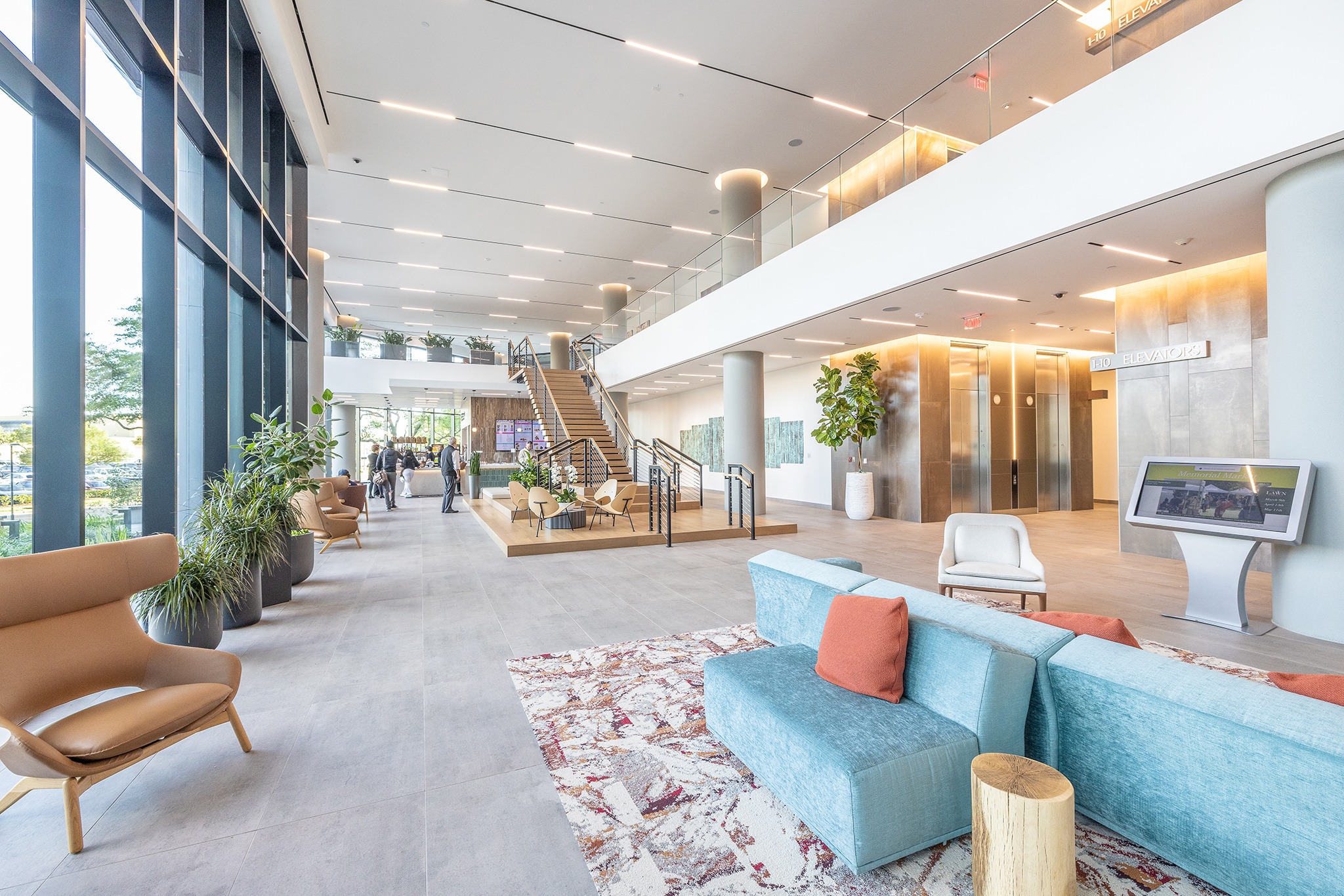 Double-height lobby at 820 Gessner Road with blue and orange sofas and the elevator bank behind