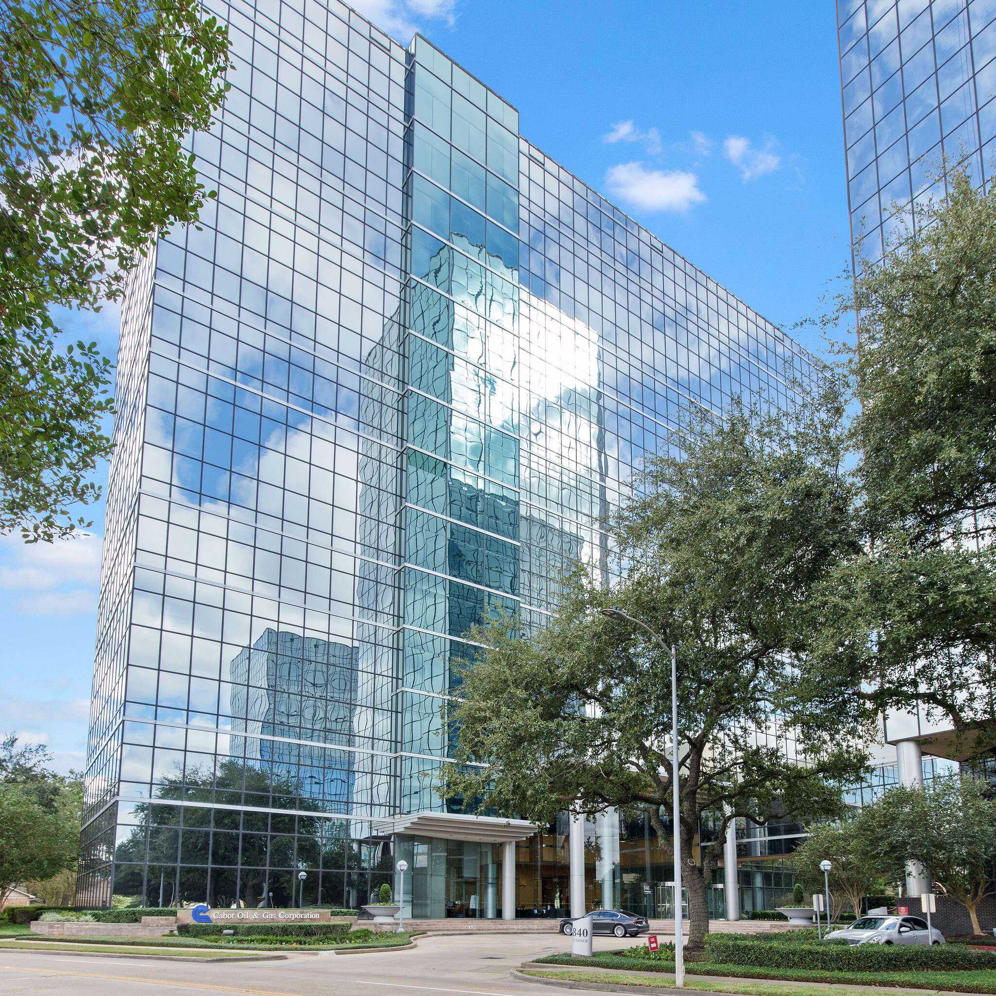 Looking up at the curved mirrored glass facade of 840 Gessner Road