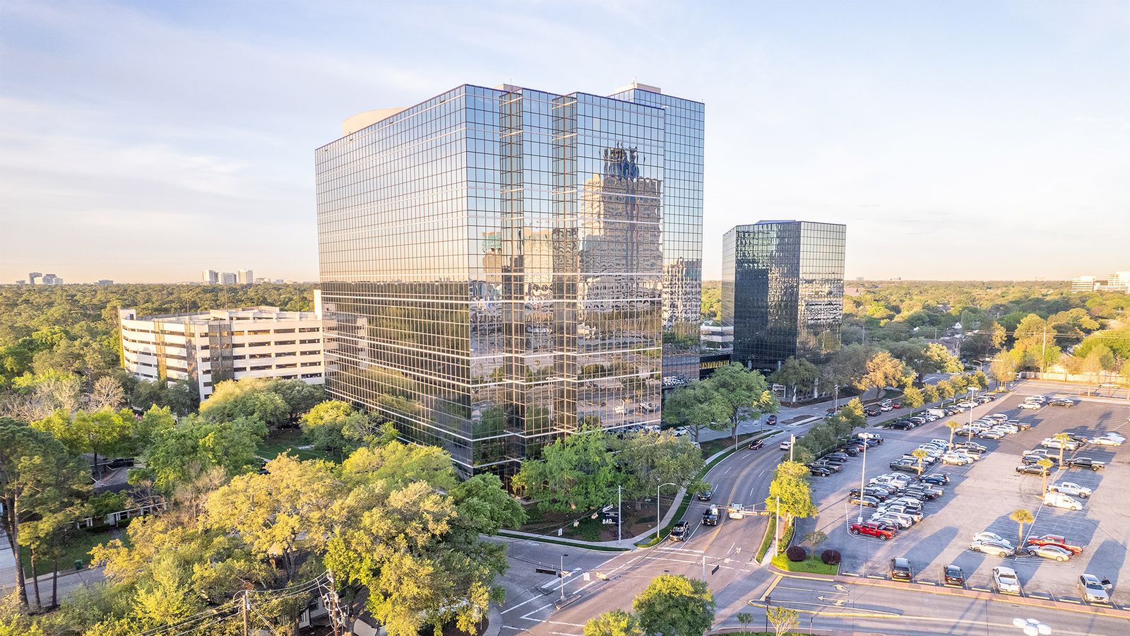 Aerial view of the office towers at 840 Gessner Road surrounded by mature trees and parking
