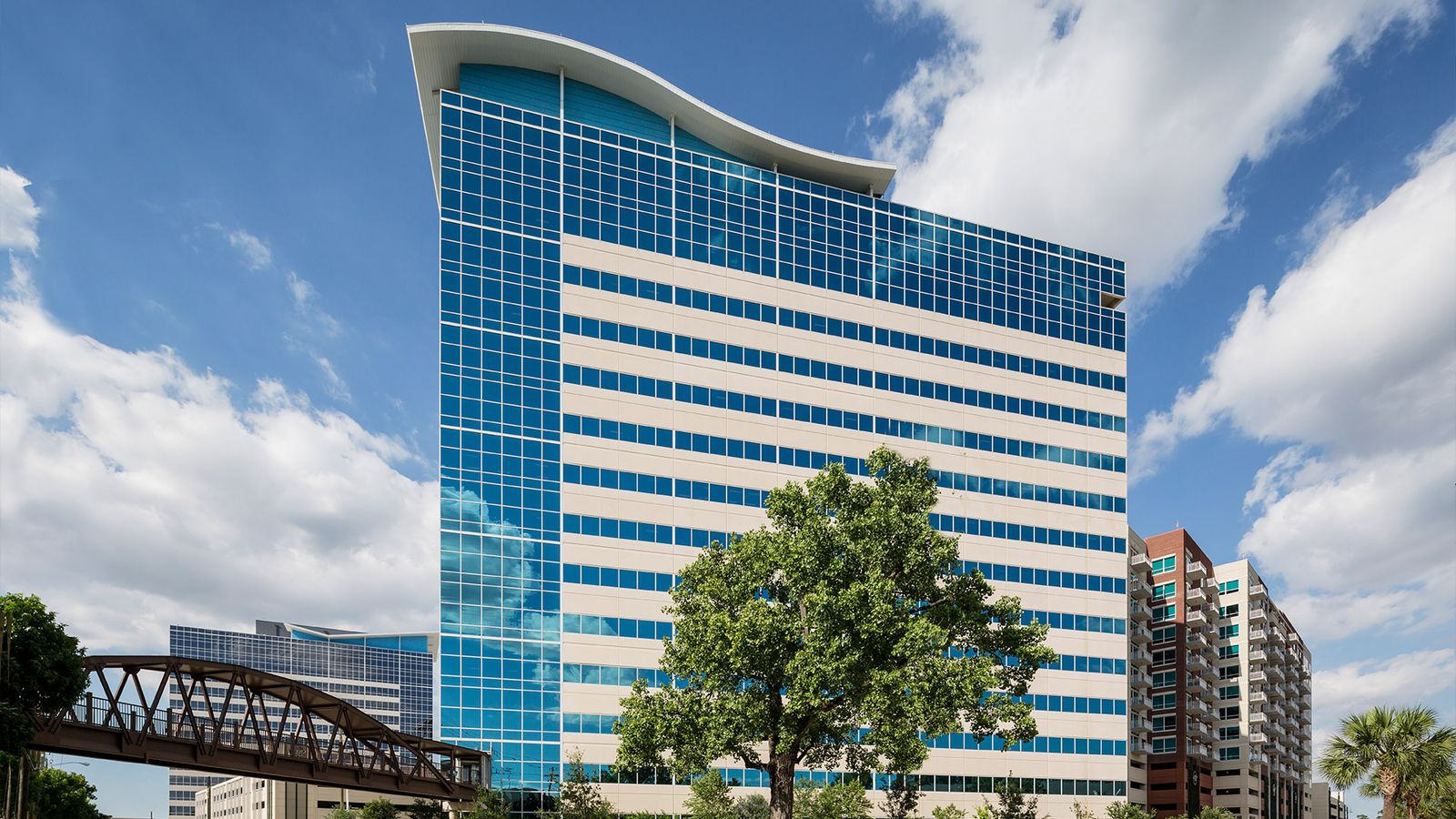 Exterior of the curved blue glass office tower at 920 Memorial City Way