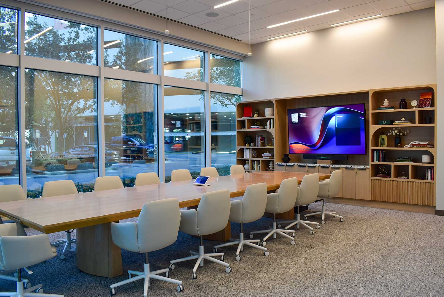 Conference room at 920 Memorial City Way with a long table, white chairs, wall screen and built-in shelving