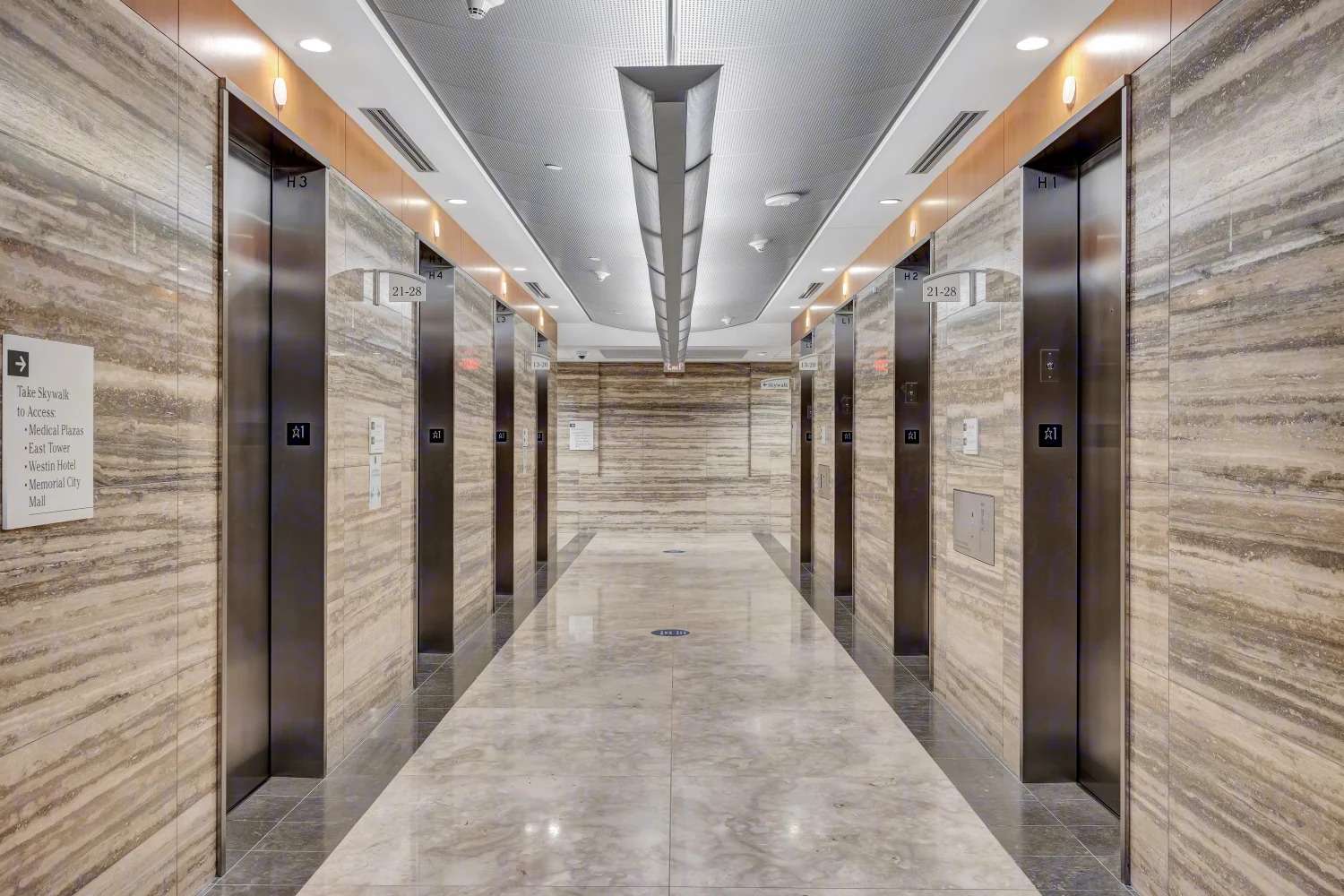 Elevator lobby at 929 Gessner Road with travertine walls and a pendant light fixture