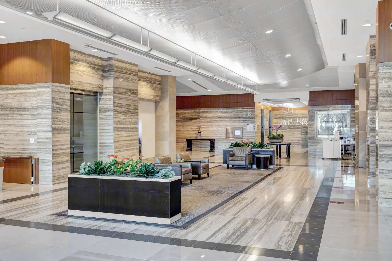 Lobby corridor at 929 Gessner Road with stone walls, planters and a security desk