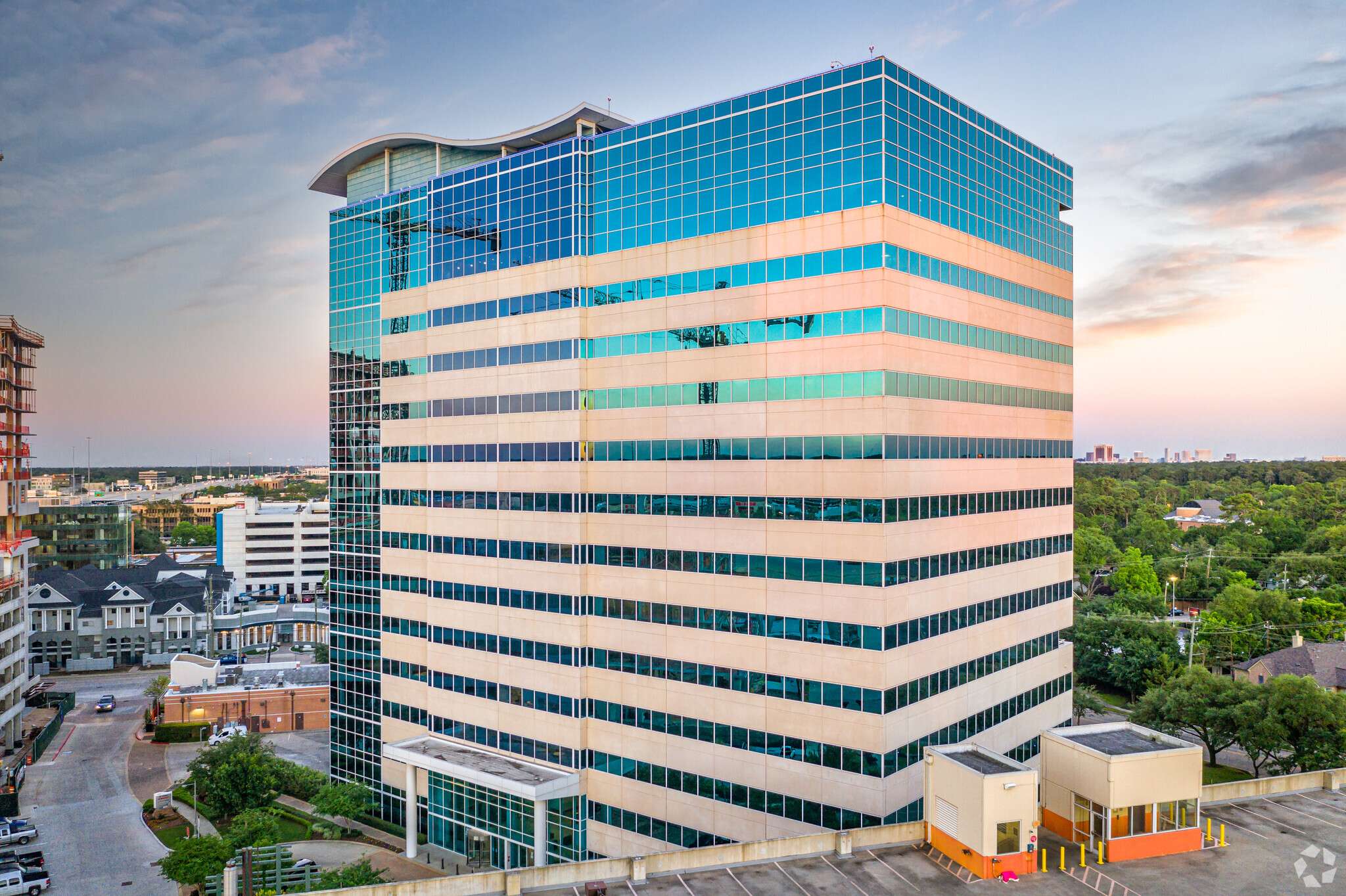 Aerial view of the blue-green glass office tower at 945 Bunker Hill Road at sunset
