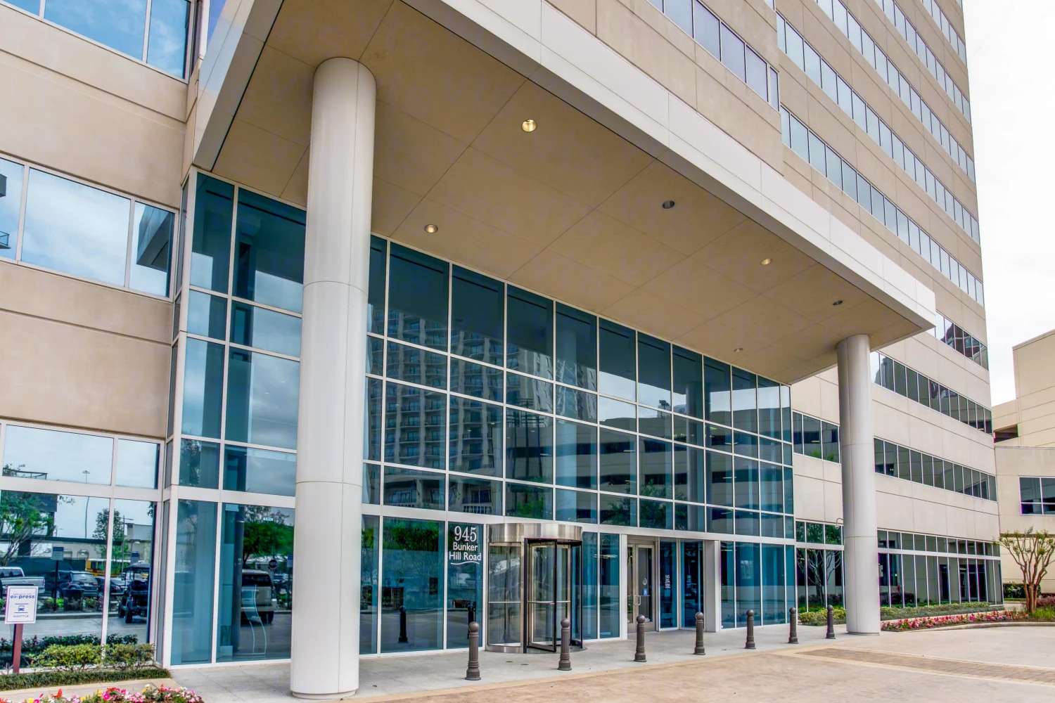 Looking up at the columned entrance and glass facade of 945 Bunker Hill Road