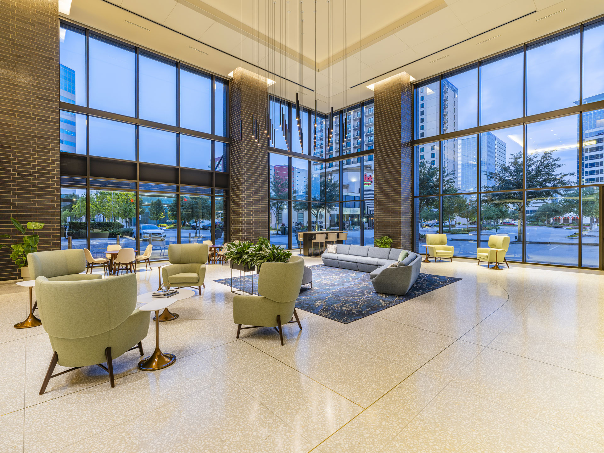 Corner lobby lounge at 9753 Katy Freeway with green armchairs and full-height glass on two sides