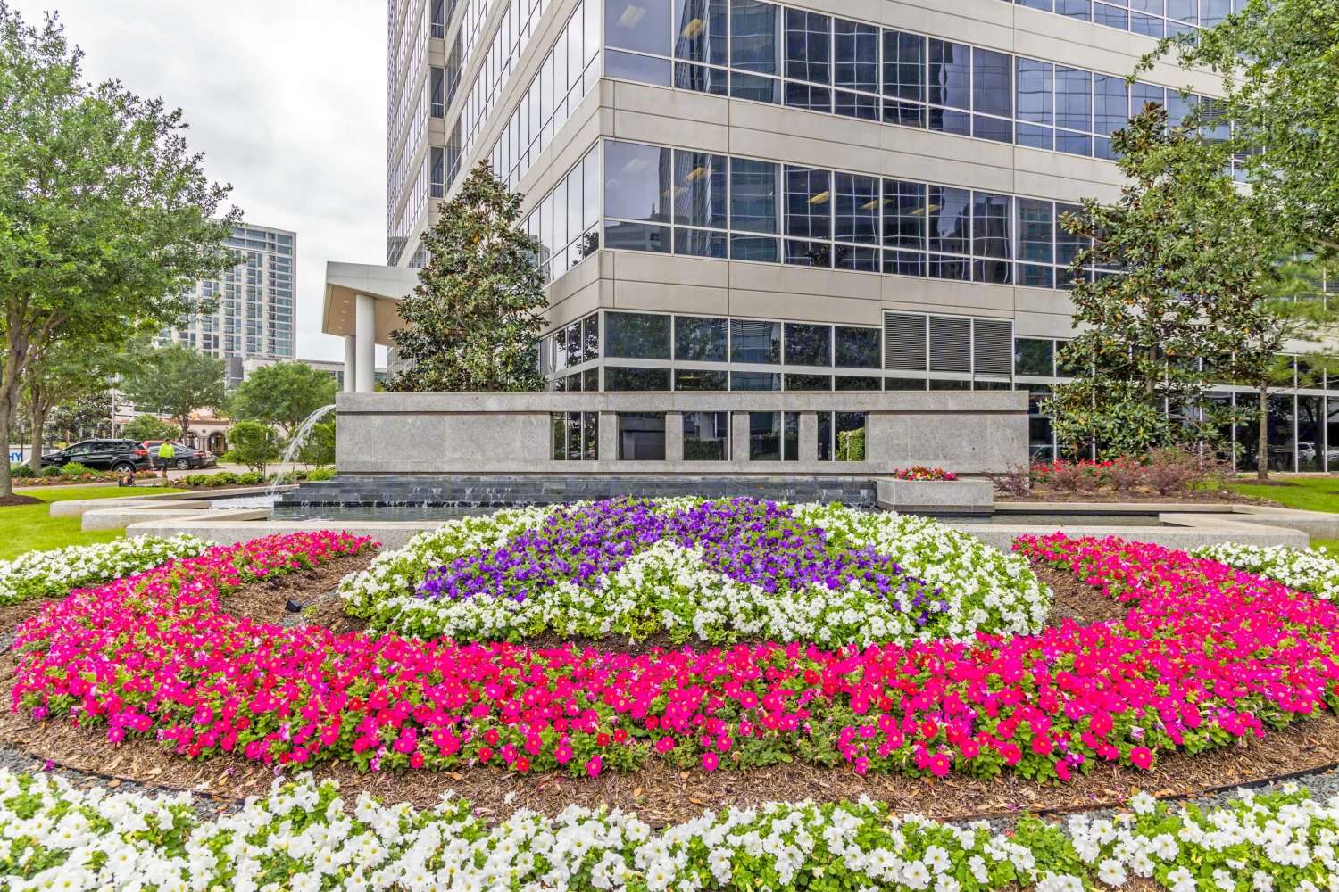 Circular flower bed of pink and purple blooms in front of the Murphy Building at 9805 Katy Freeway