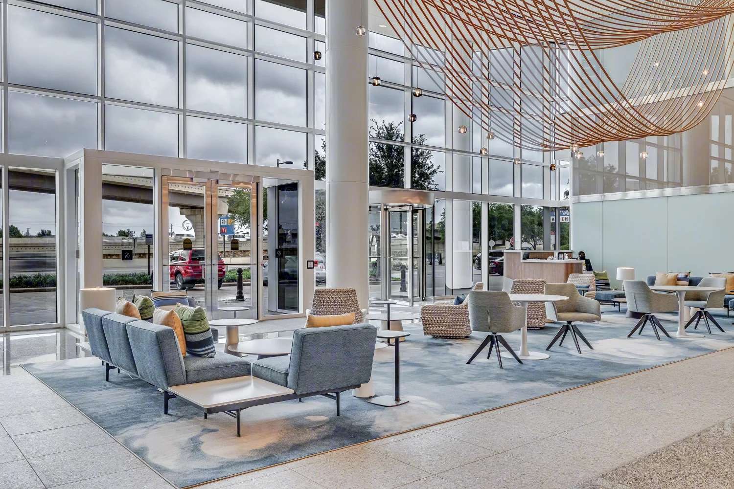 Lobby lounge at the Murphy Building with grey armchairs, glass walls and a copper chain ceiling feature