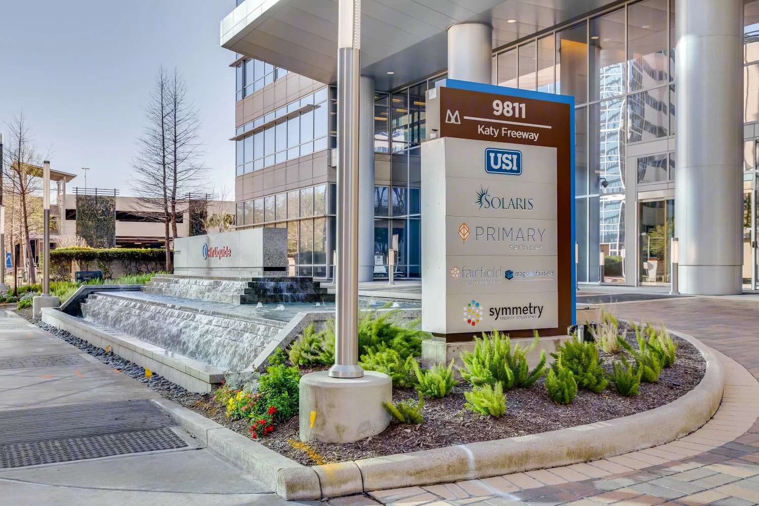 Monument tenant sign at 9811 Katy Freeway, set in landscaping beside a water feature