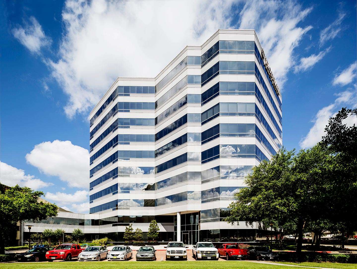Exterior of the banded glass office building at 9821 Katy Freeway, with surface parking in front