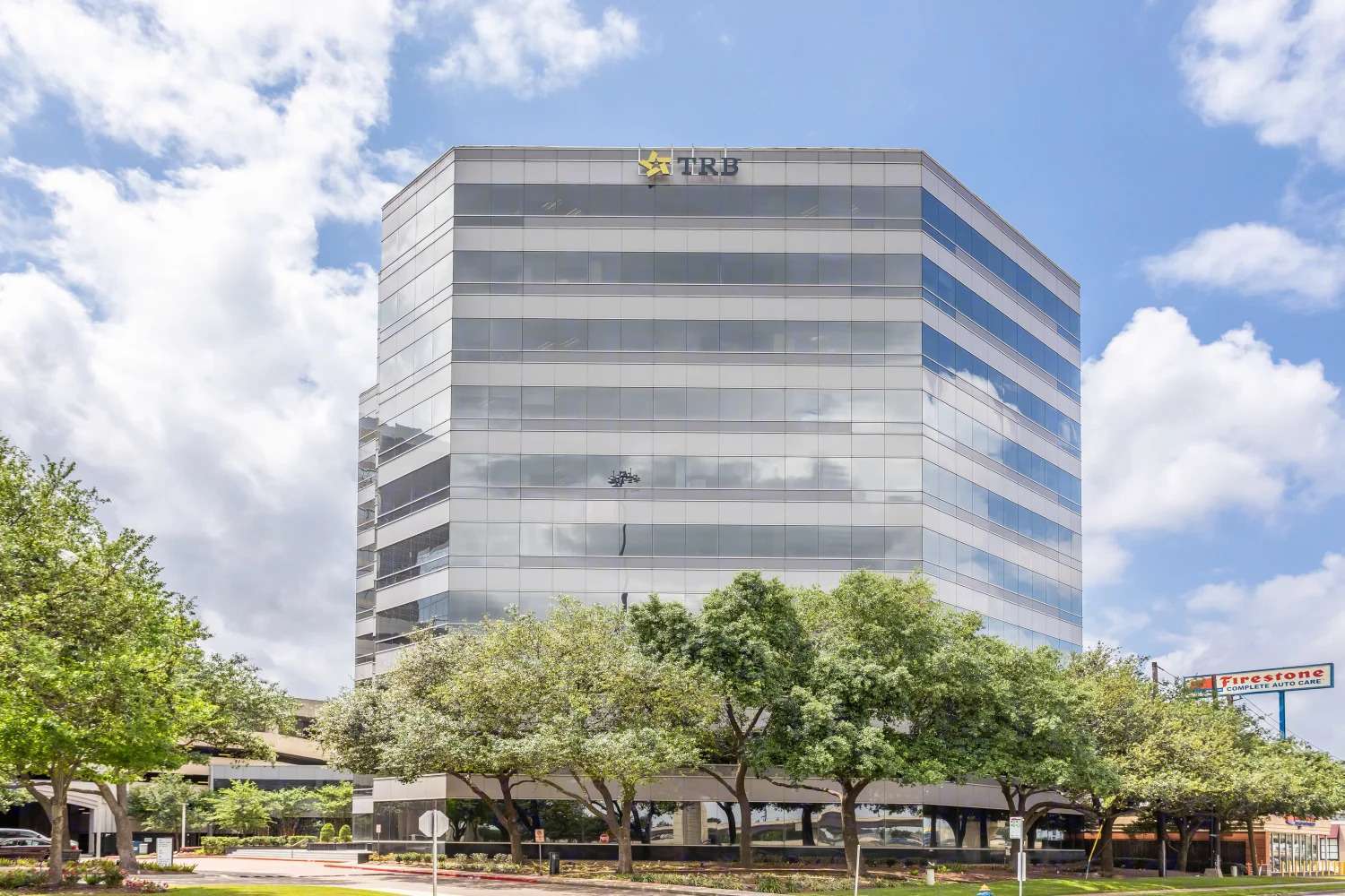Exterior of the grey banded office building at 9821 Katy Freeway framed by trees