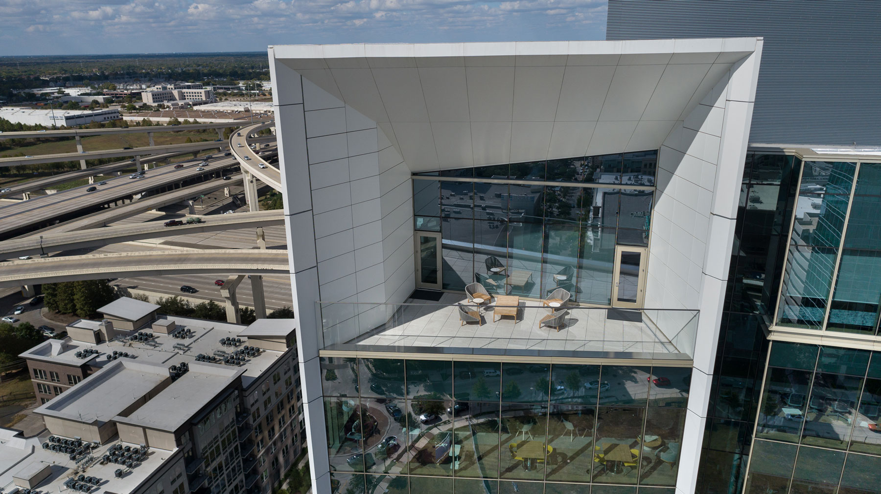 Angular glass canopy of 990 Town & Country seen from above, with the freeway interchange behind
