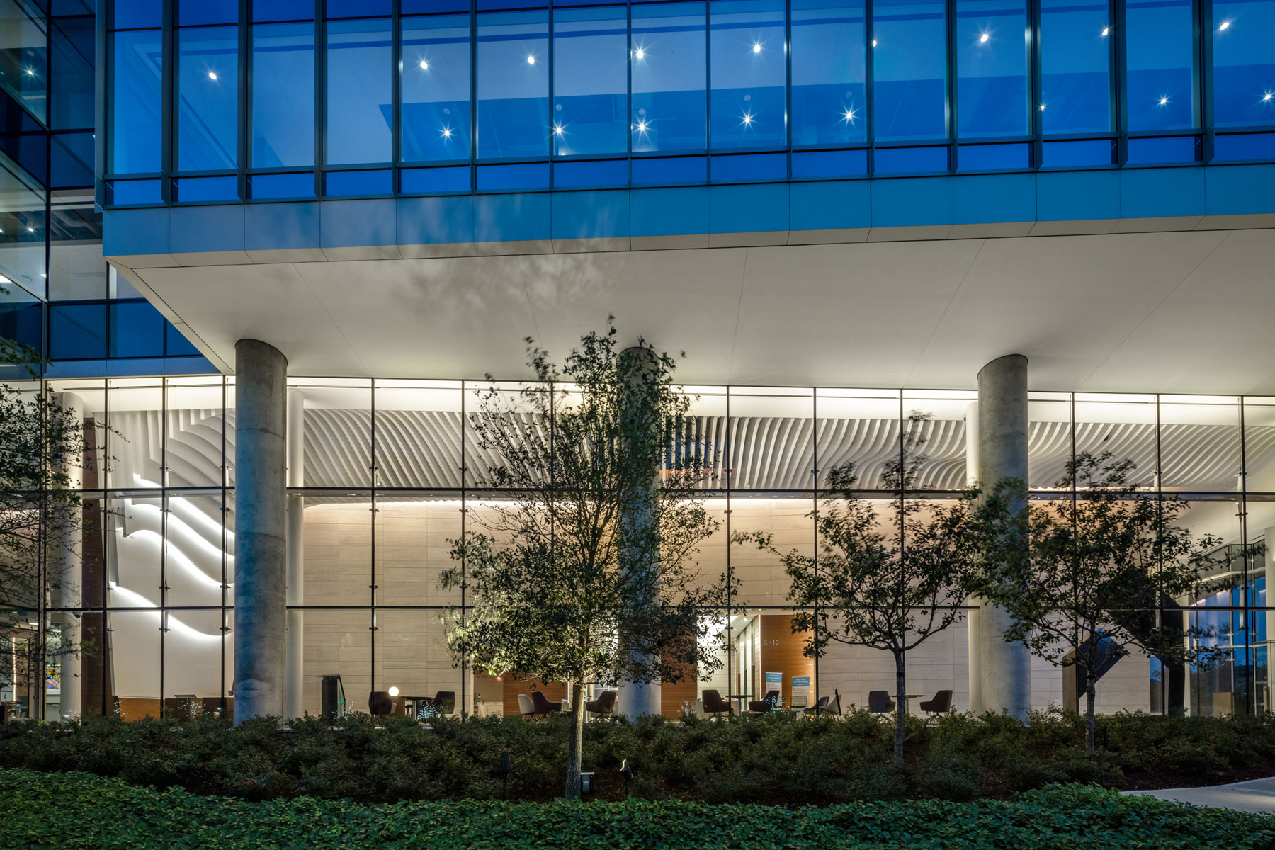 Exterior of 990 Town & Country at dusk, with its blue glass upper facade above landscaped beds