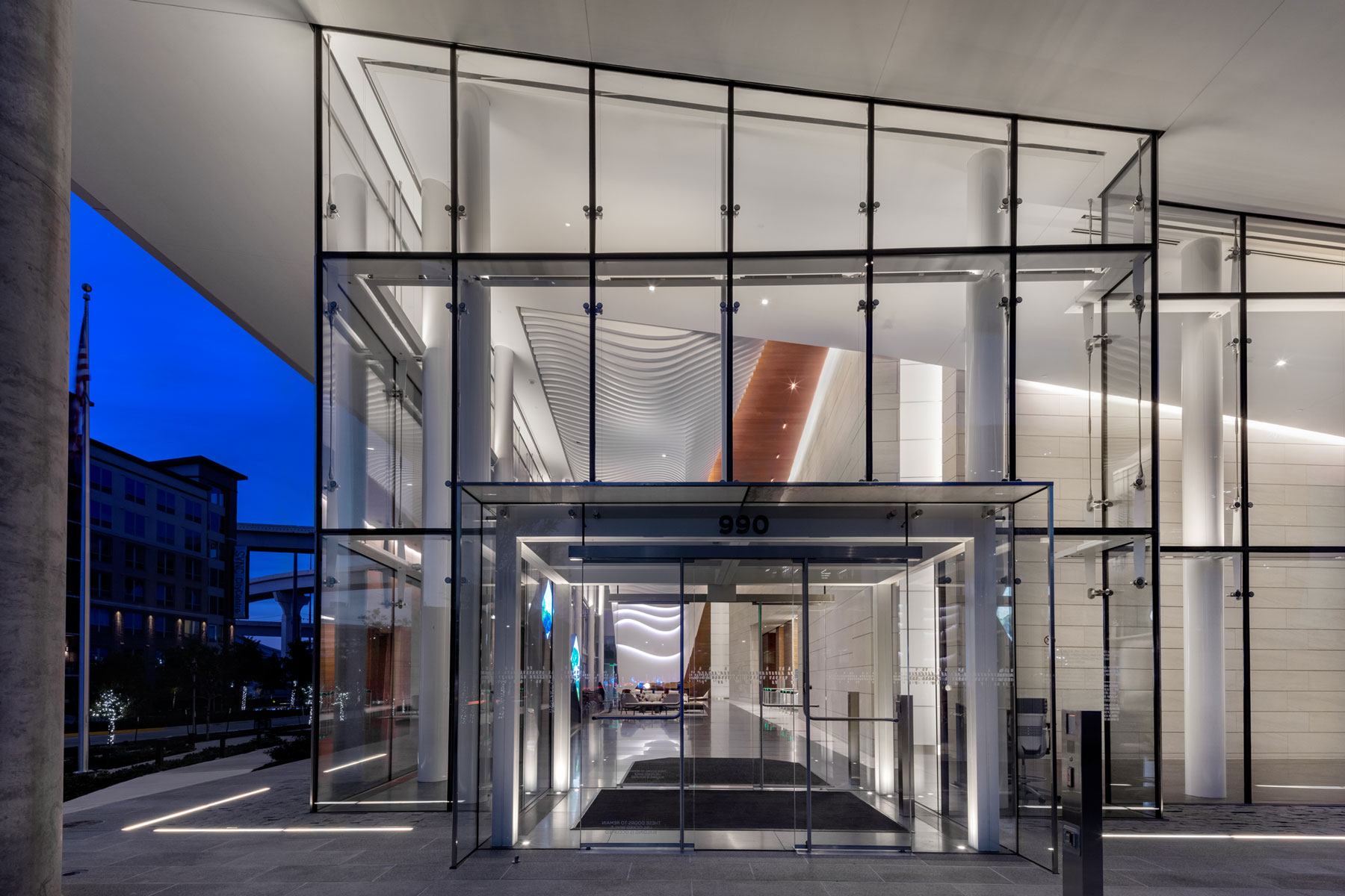 Glass elevator lobby at 990 Town & Country lit at night