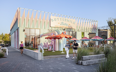 Exterior of Buttermilk Baby at M-K-T Heights, with a scalloped pastel facade and patio umbrellas