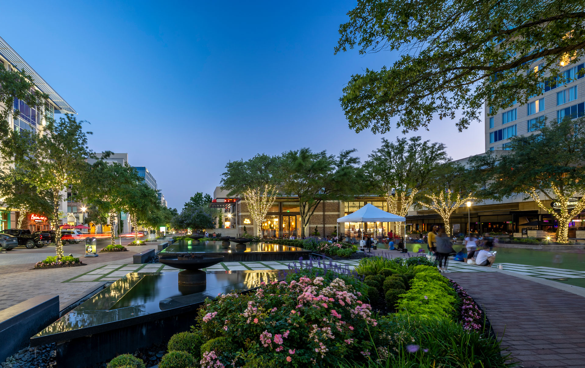 Landscaped water feature at CityCentre in the evening, edged with flowering beds