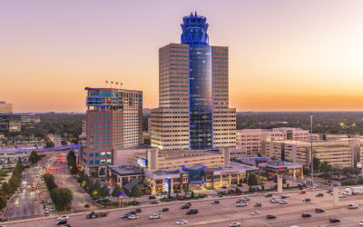 Aerial view of the Memorial City district at sunset, with its blue-lit tower at the center