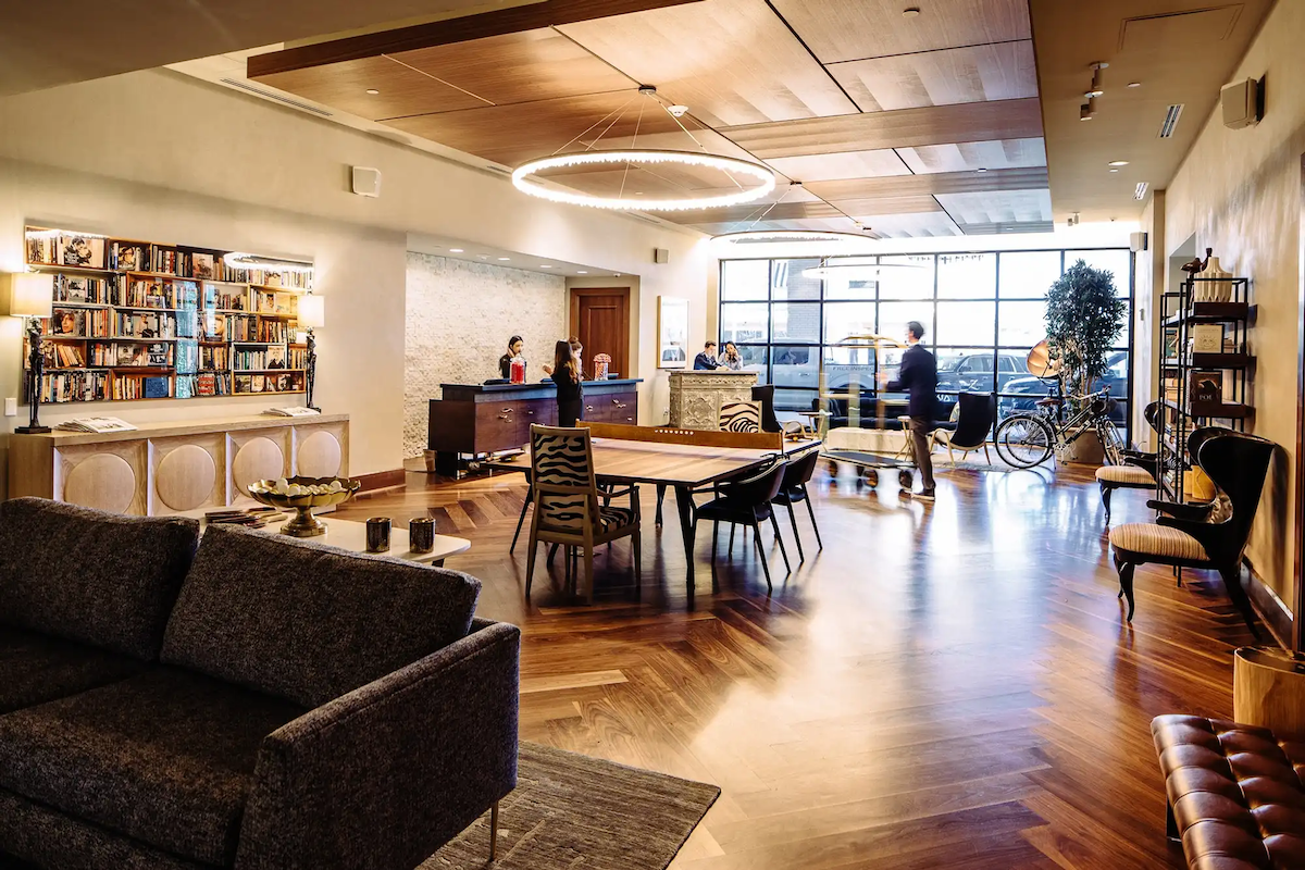 Library lounge at Hotel ZaZa Memorial with bookshelves, a sofa and herringbone wood flooring
