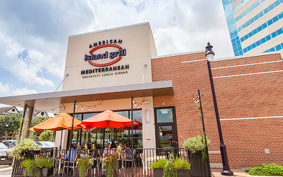 Island Grill Exterior of American Island Grill Mediterranean restaurant at Memorial City Village, with orange patio umbrellas over its outdoor seating