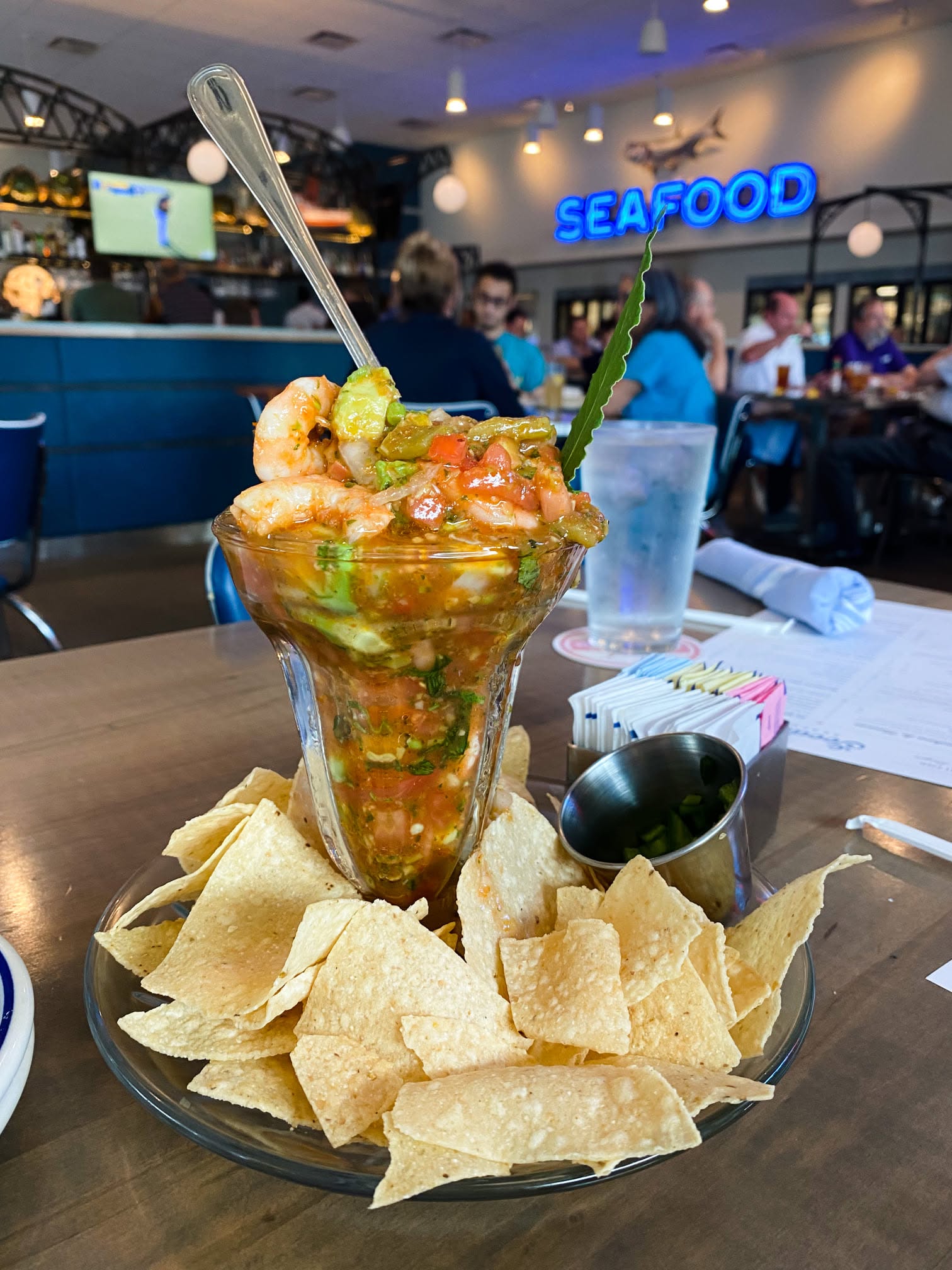 Tall seafood cocktail with shrimp and avocado served with tortilla chips inside Goode Co. Seafood
