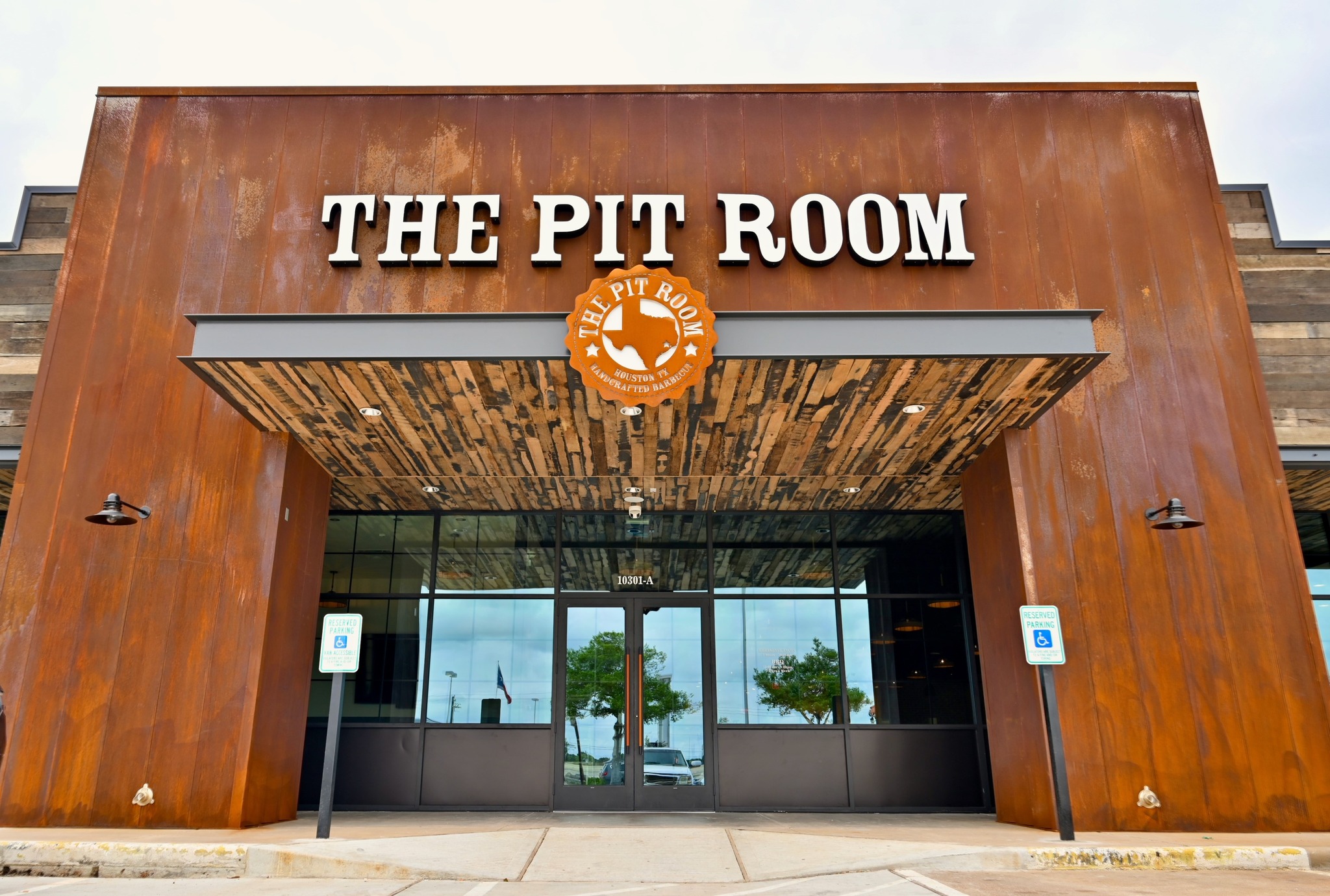 Wood-clad entrance to The Pit Room barbecue restaurant, with the restaurant name above the doors