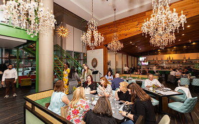 Liberty Kitchen Diners seated at tables in a restaurant at Memorial City Village beneath large ornate chandeliers