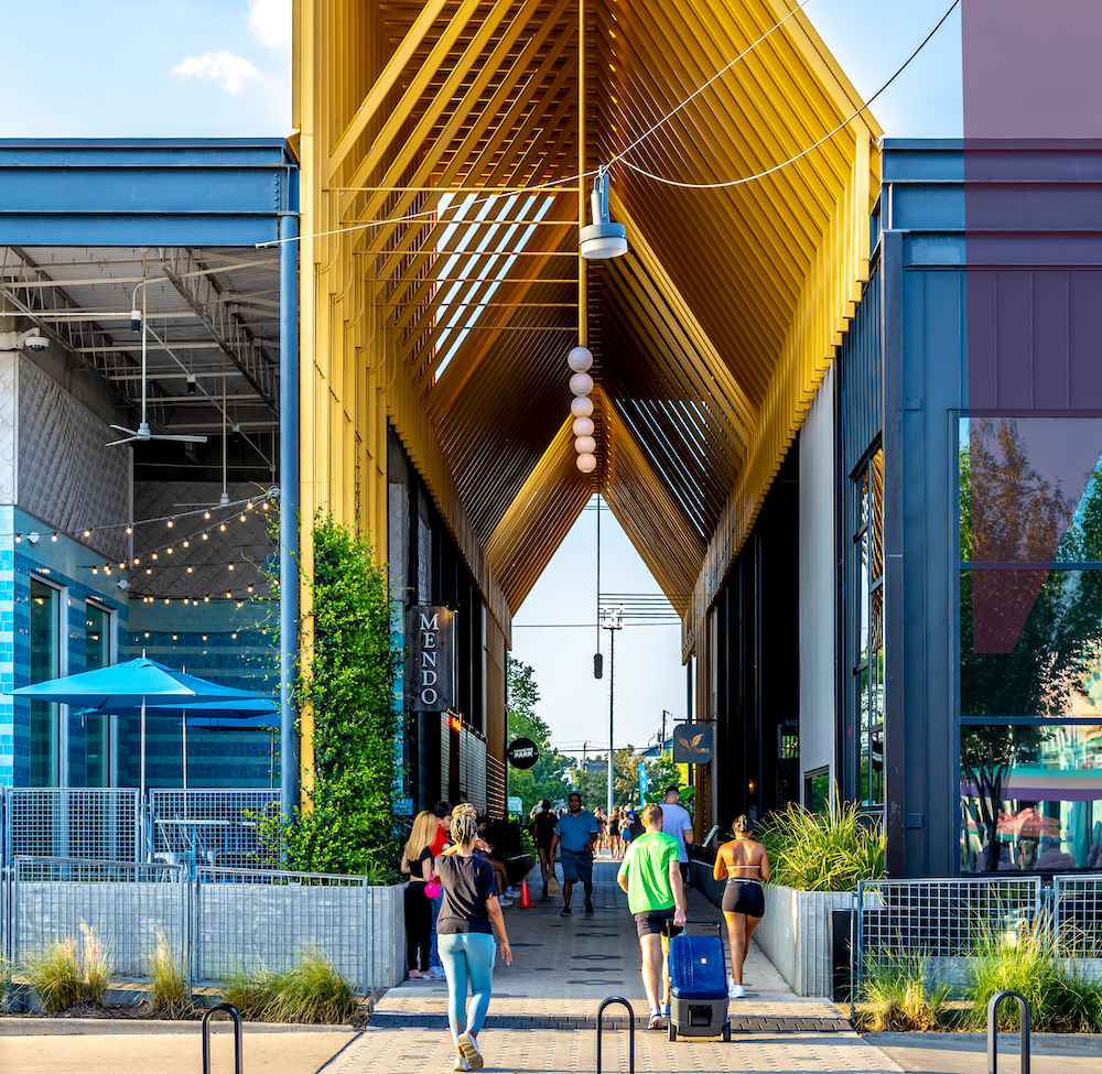 Outdoor plaza at M-K-T Heights beneath the angular yellow canopy structure