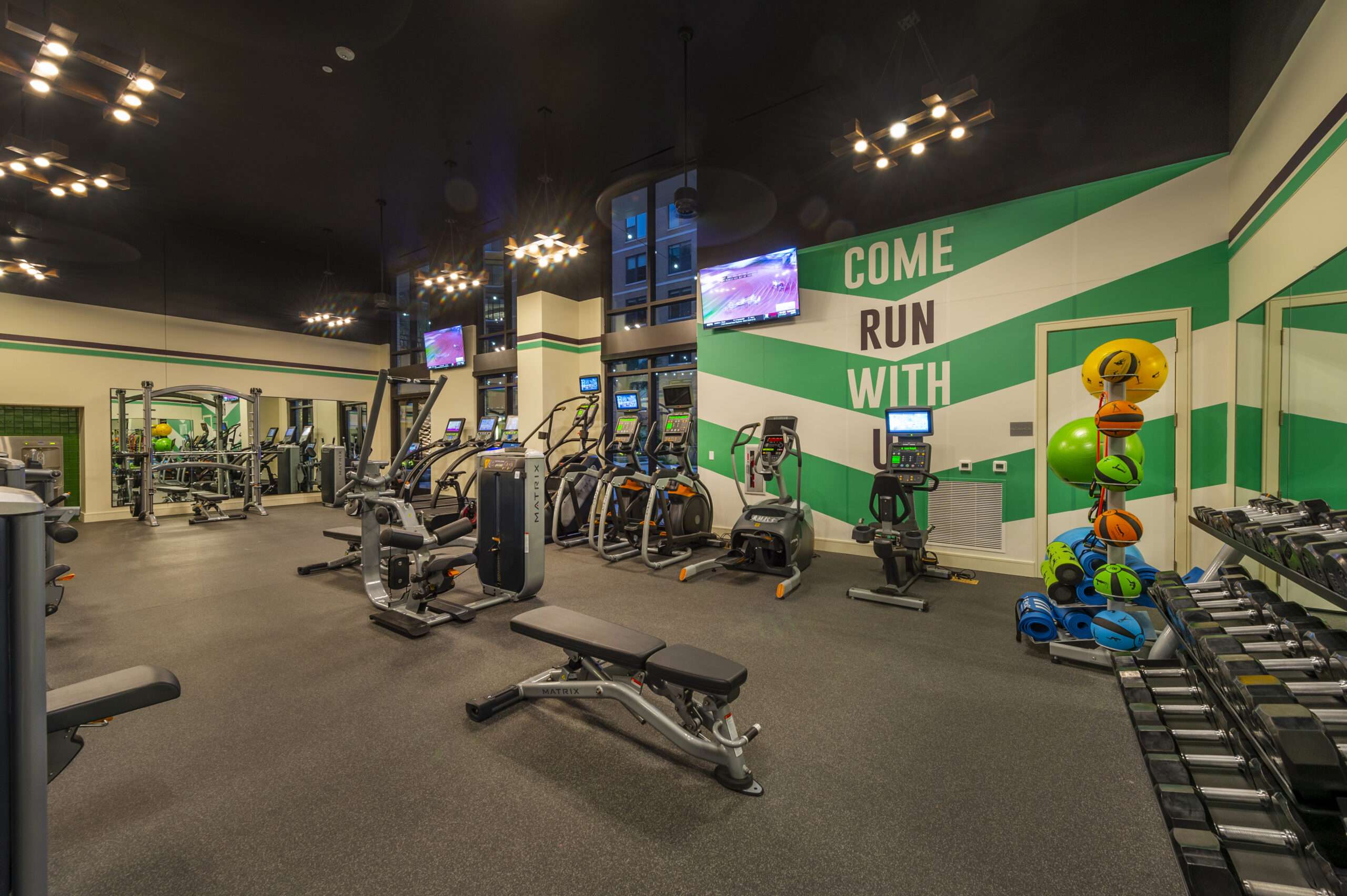 McAdams-05 Fitness center at The McAdams with cardio equipment and a green accent wall with painted lettering