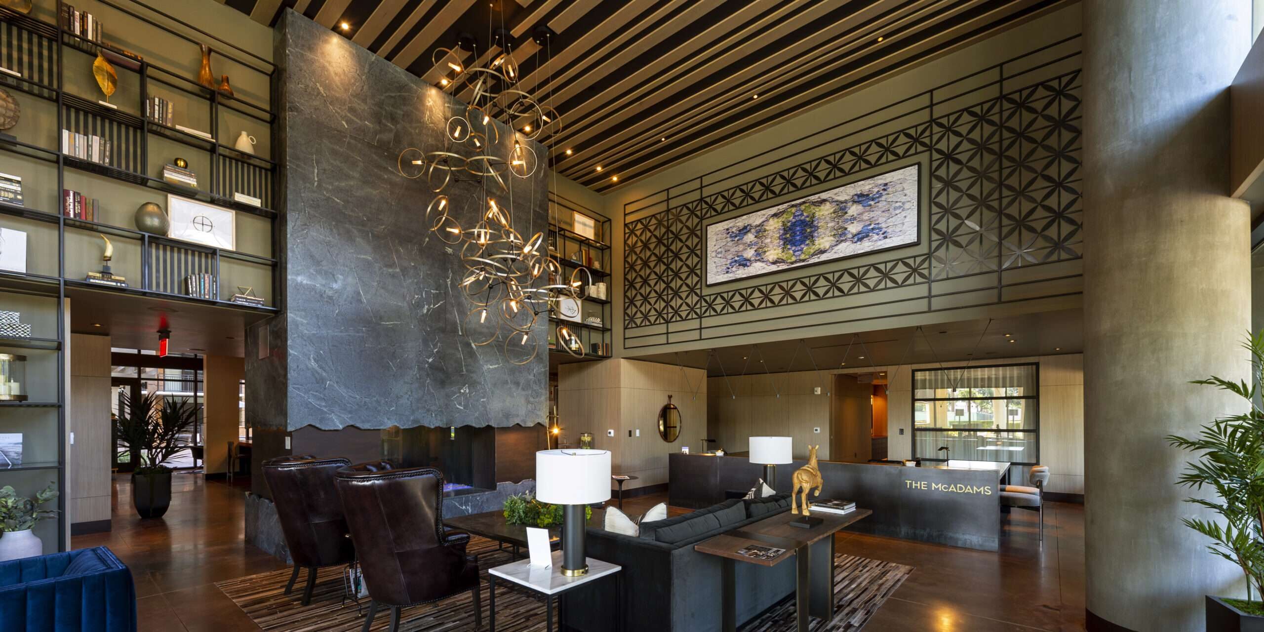 Double-height lounge at The McAdams with bookshelves, a chandelier and grouped seating