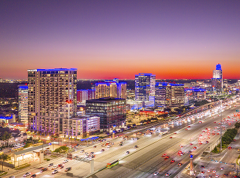 Mem-City-Mall-Connected Aerial view of Memorial City at dusk, with lit towers and freeway light trails