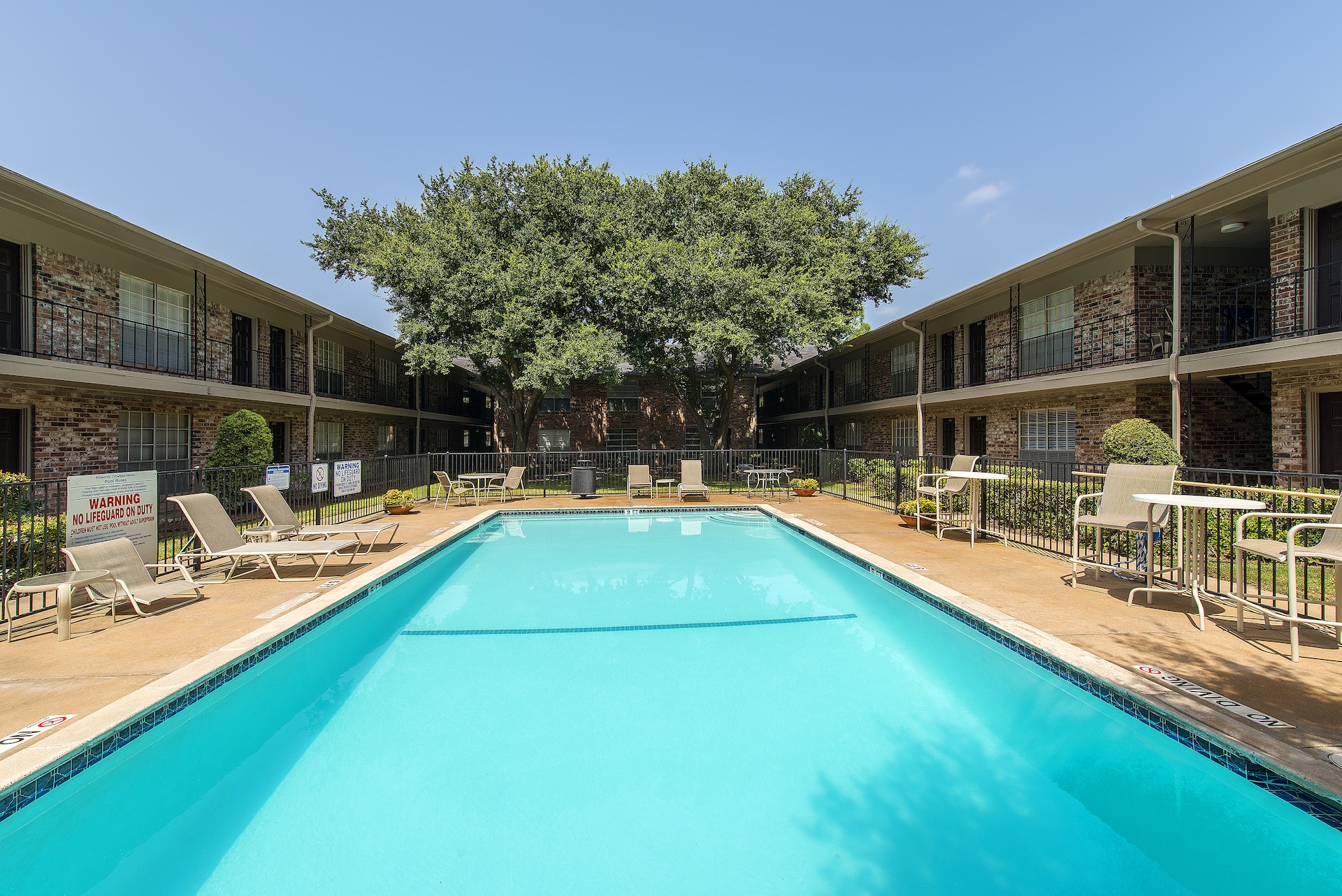 Courtyard swimming pool at Memorial City Apartments, enclosed by the two-story buildings and a large oak tree
