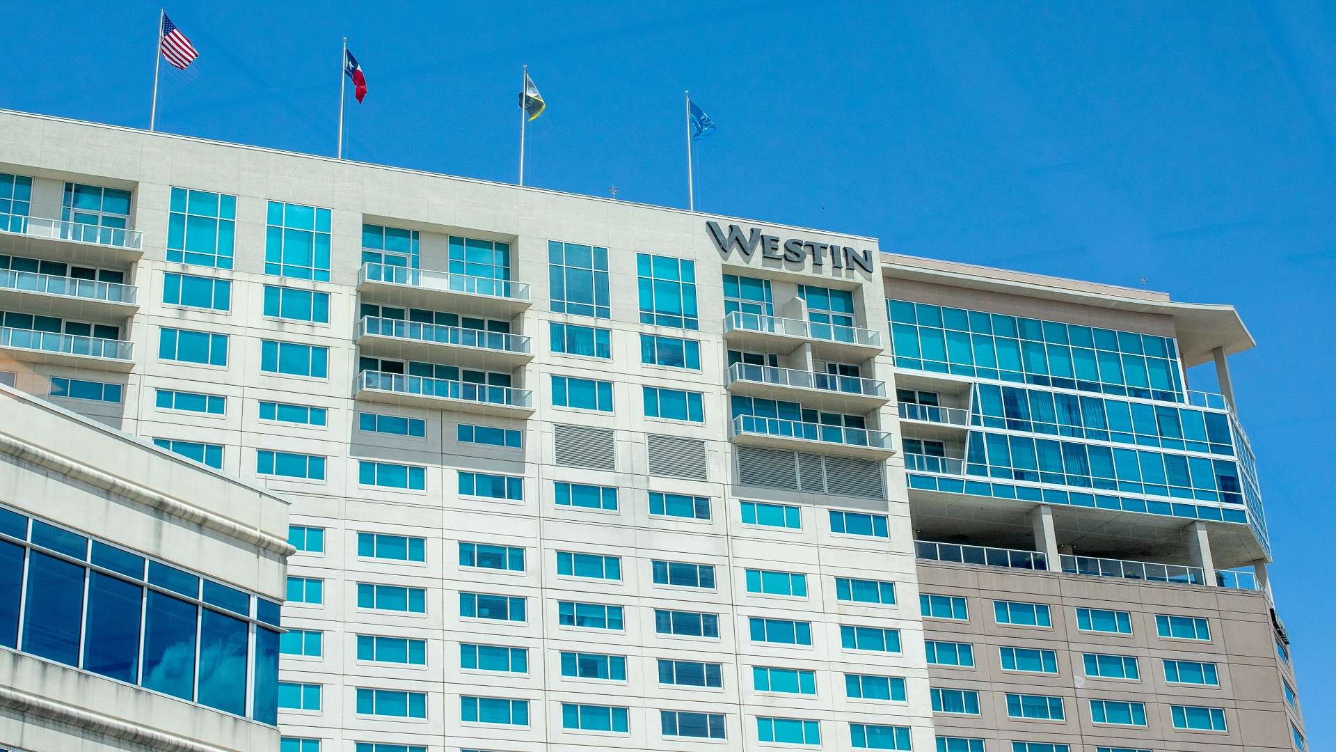 Exterior of The Westin Memorial, a blue-green glass tower with the Westin sign at the roofline