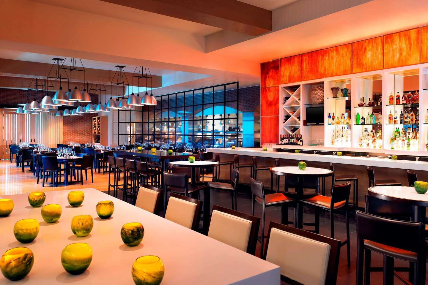 Bar and lounge at The Westin Memorial with an orange-lit back bar and a long communal table
