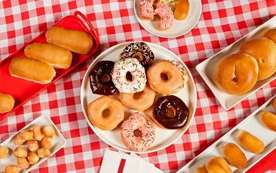 Shipley Assorted glazed and frosted doughnuts and doughnut holes arranged on a red and white checkered cloth