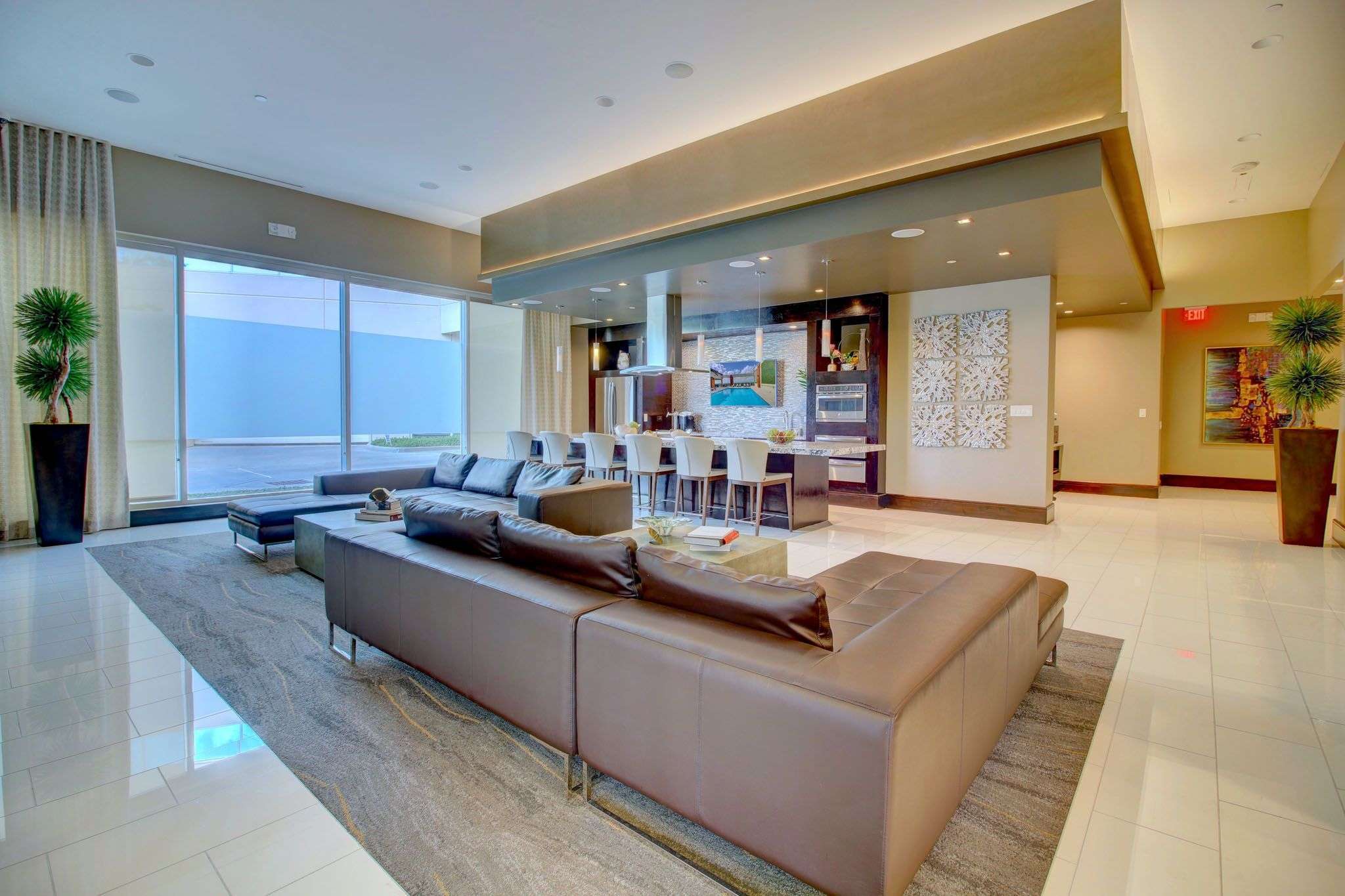 Resident lounge at The Fountains with a sectional sofa facing a window wall over tile floors