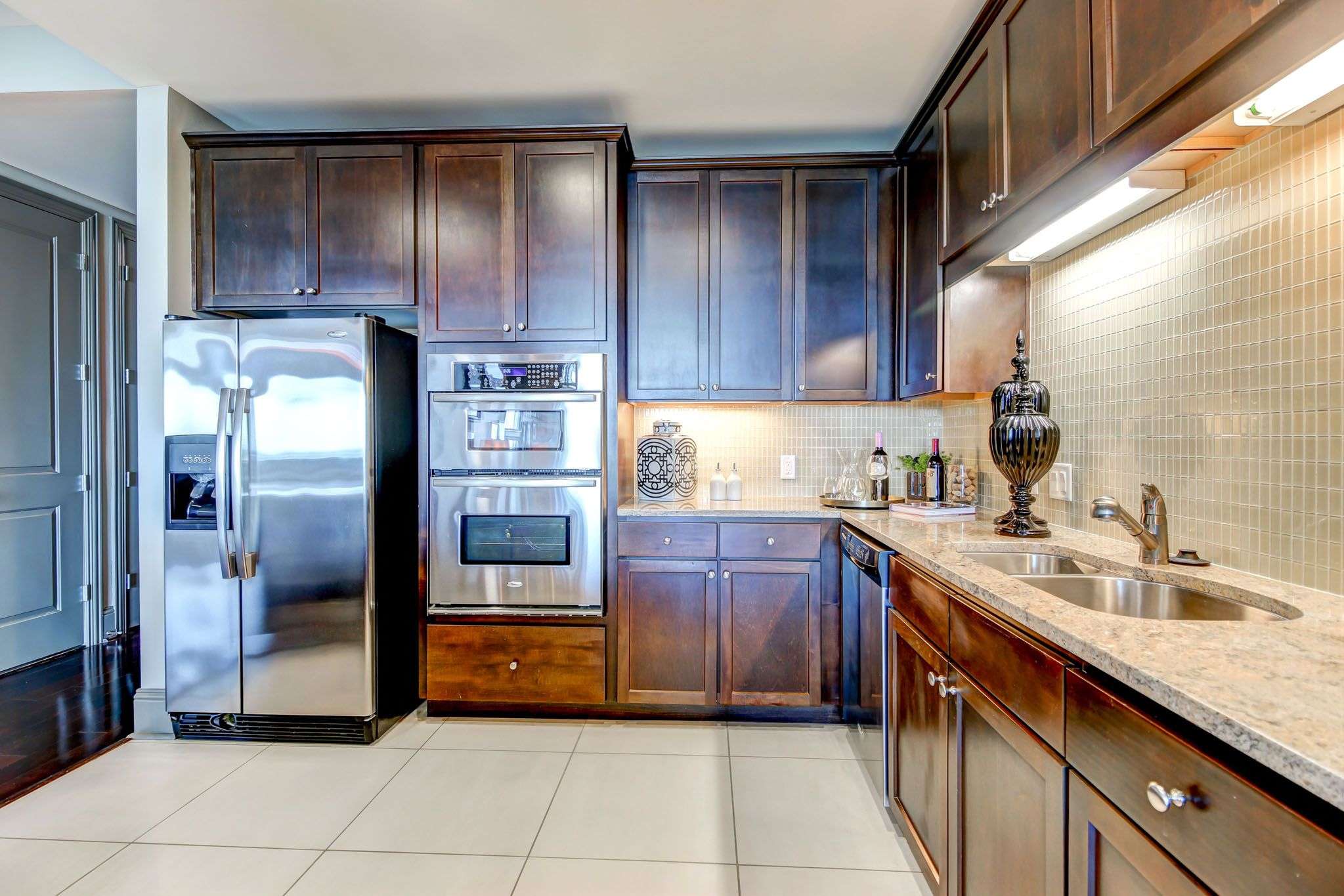Apartment kitchen at The Fountains with dark wood cabinets, stainless appliances and a tile backsplash
