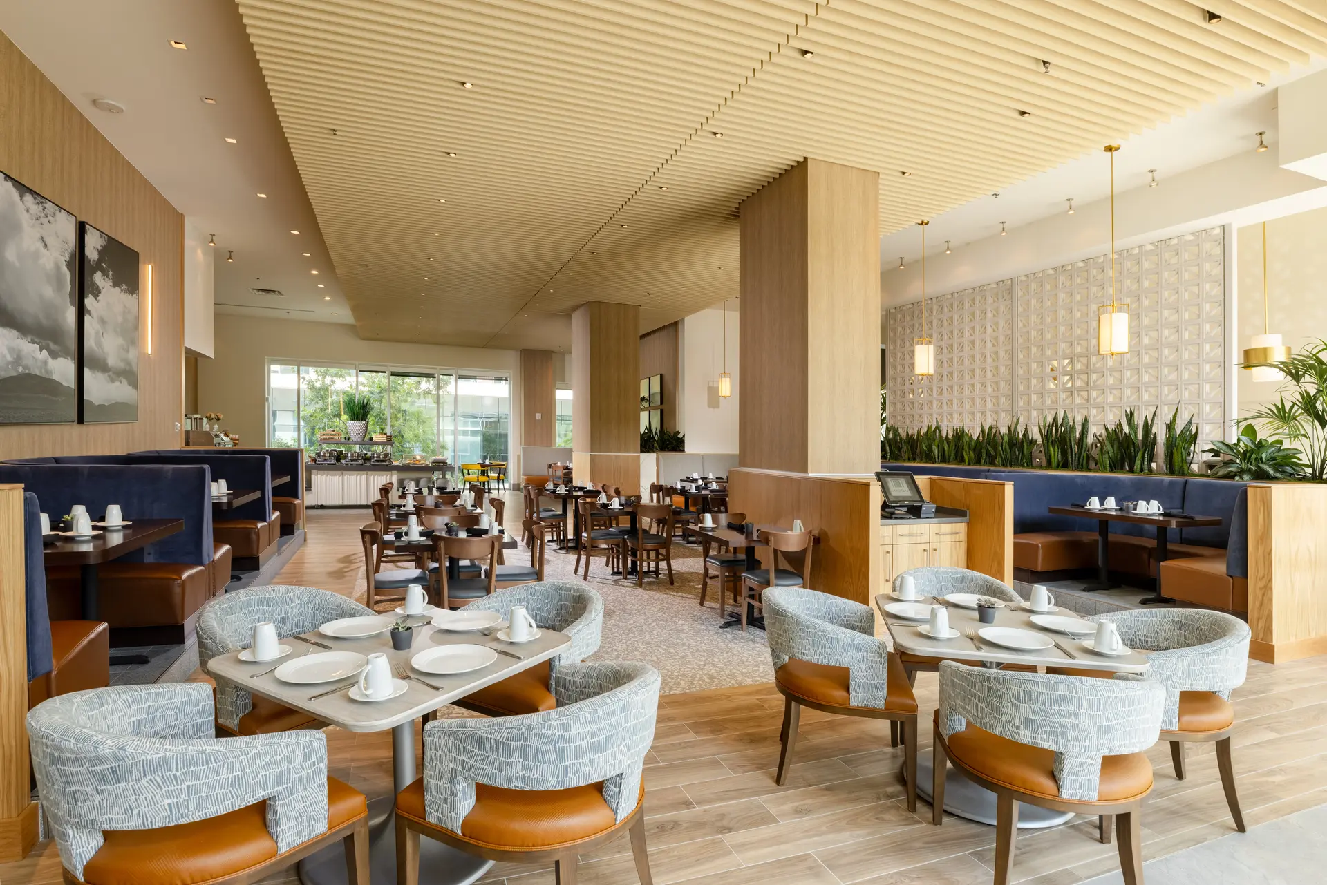 Dining room at The Moran Hotel with round tables, teal upholstered chairs and a slatted wood ceiling