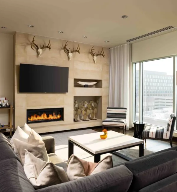 Lounge at The Moran Hotel with a linear fireplace, sectional sofa and antler decor above the mantel