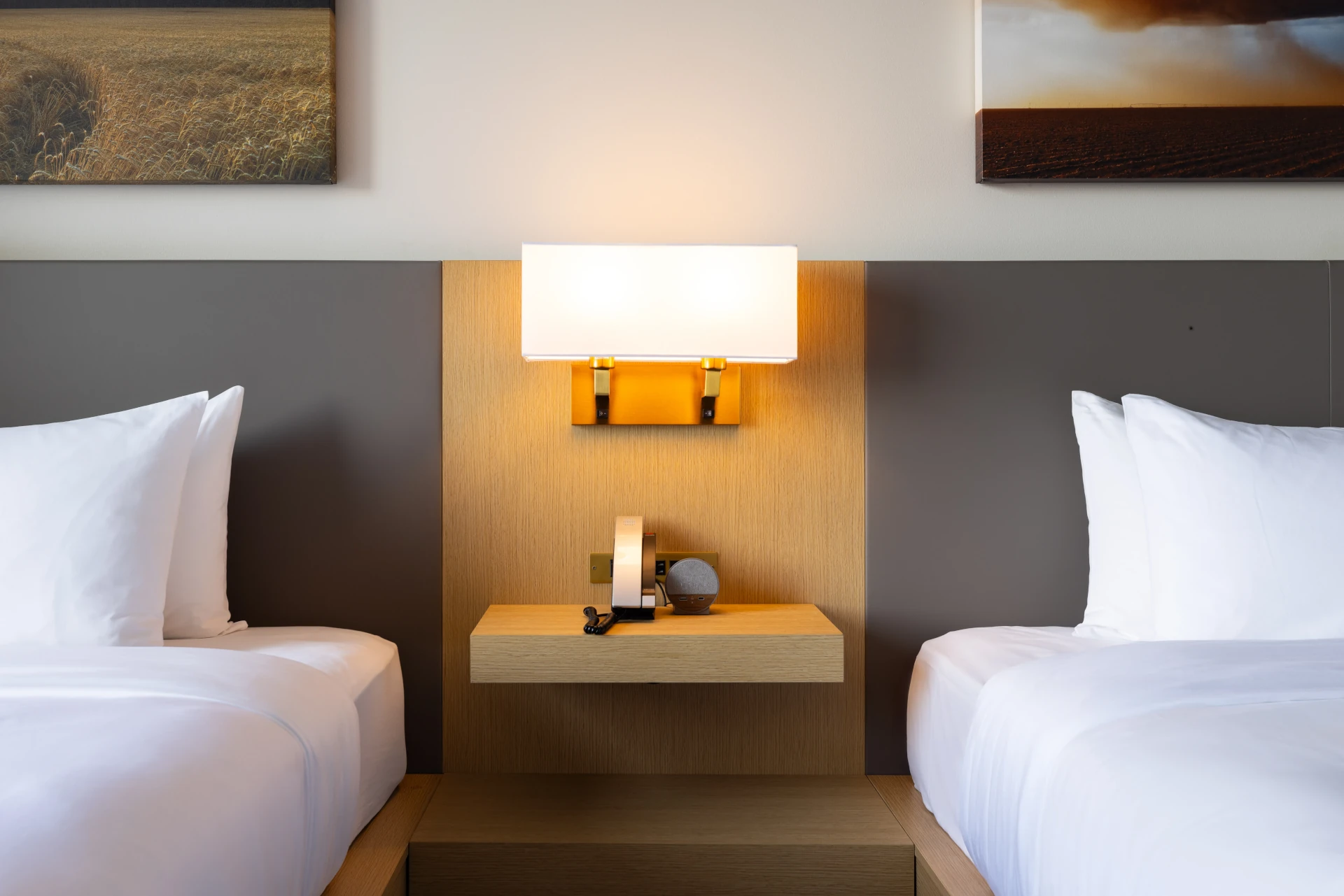 Two beds side by side at The Moran Hotel sharing a nightstand and wall-mounted sconce