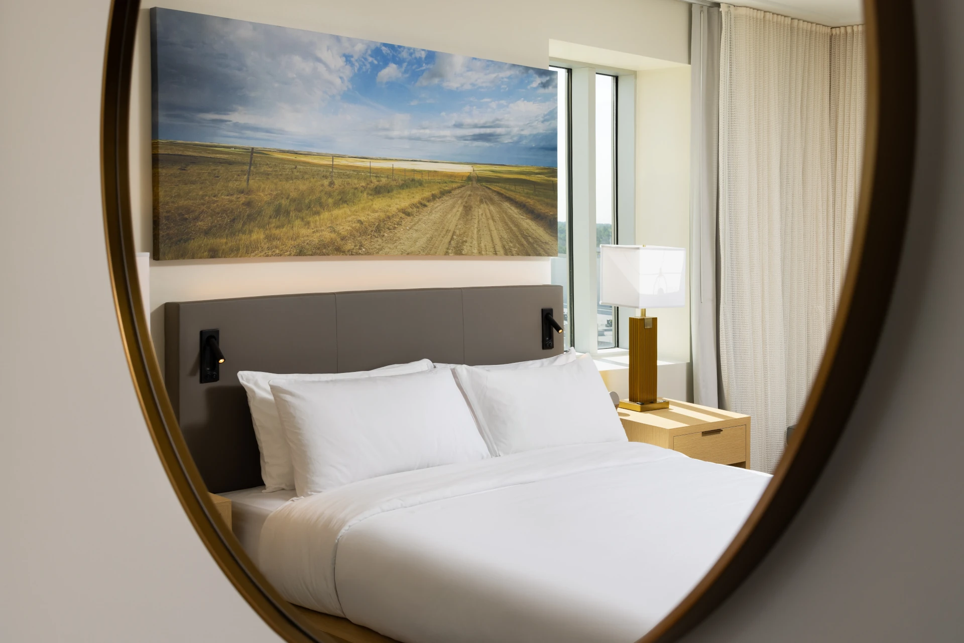 Guest room bed at The Moran Hotel reflected in a large round mirror