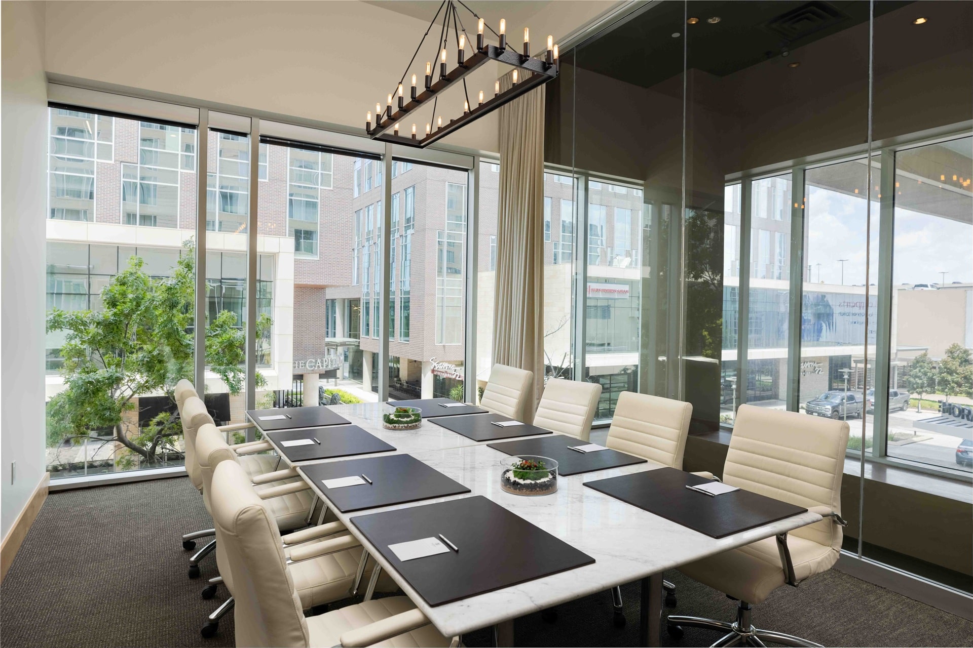 Glass-walled meeting room at The Moran Hotel with a long conference table and leather chairs