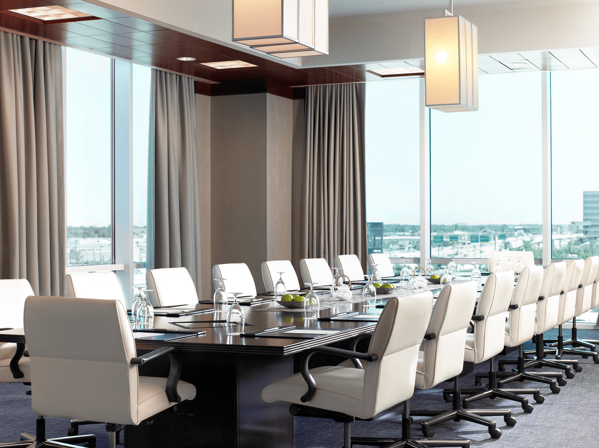 Boardroom at The Westin Memorial with a long conference table, white chairs and floor-to-ceiling city views