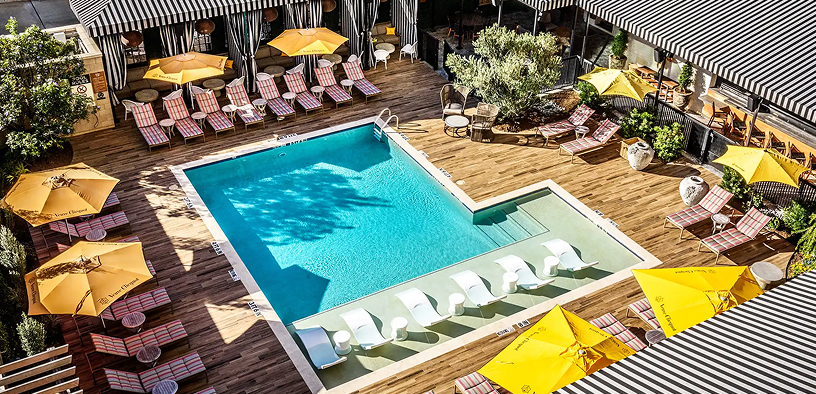 Overhead view of The Beach Club pool deck at Hotel ZaZa Memorial, with yellow umbrellas and cabanas